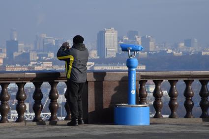 Москва.  Мужчина фотографирует  на смотровой площадке Воробьевых гор.