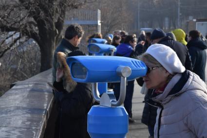 Москва.  Женщина смотрит в бинокль на смотровой площадке Воробьевых гор.