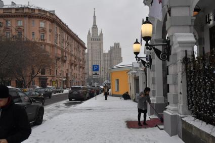 Москва.  Служащая чистит ковровую дорожку  у посольства на Поварской улице. на Поварской улице.