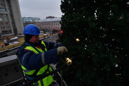 Москва. Рабочий вешает игрушки на елку на Чистых прудах.