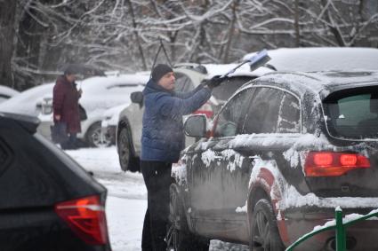 Москва. Мужчина очищает от снега автомобиль.