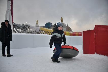 Москва. Мальчик с тюбингом на горке.