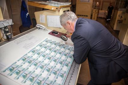Пермь. Сотрудник фабрики Гознак просматривает листы с денежными купюрами  номиналом 1000 рублей.