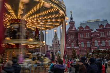 Москва.  Дети катаются на карусели на  Манежной Площади.