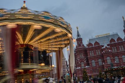 Москва.  Дети катаются на карусели на  Манежной Площади.