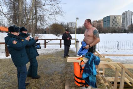 Москва. Сотрудники пожарно-спасательного центра фотографируют  мужчину  во время крещенского купания на Воронцовских прудах.