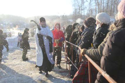 Иркутск. Священник окропляет верующих святой водой во время  празднования Крещения Господня.