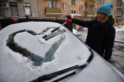 Москва. Девушка очищает машину от снега.