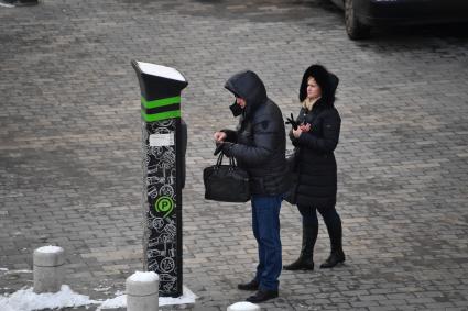 Москва. Мужчина оплачивает парковку автомобиля через паркомат.