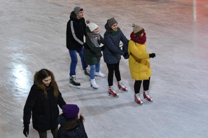 Москва.  Молодые люди катаются на катке в Парке Горького.