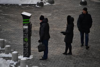 Москва. Мужчина оплачивает парковку автомобиля через паркомат.