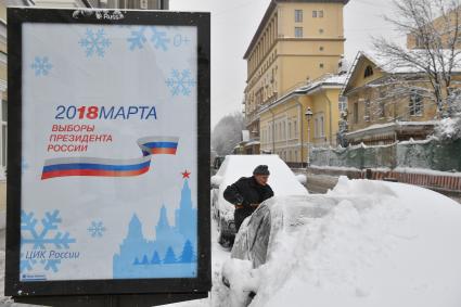 Москва.  Мужчина очищает машину от снега.