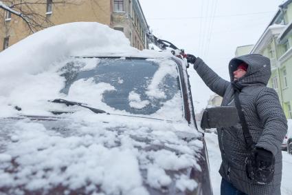 Санкт-Петербург.  Мужчина очищает машину от снега.