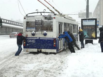 Москва.  Пассажиры толкают троллейбус во время сильного снегопада.