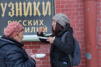 Санкт-Петербург.  Китайские туристки едят блины во время празднования  `Широкой Масленицы`  в Петропавловской крепости.