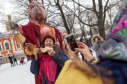 Санкт-Петербург.  Женщина фотографируется у чучела  во время празднования  `Широкой Масленицы`  в Петропавловской крепости.