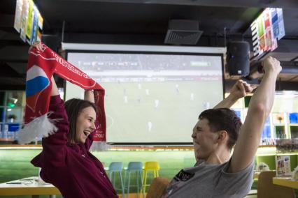 Самара. Молодой человек и девушка в спорт-баре радуются победе команды.