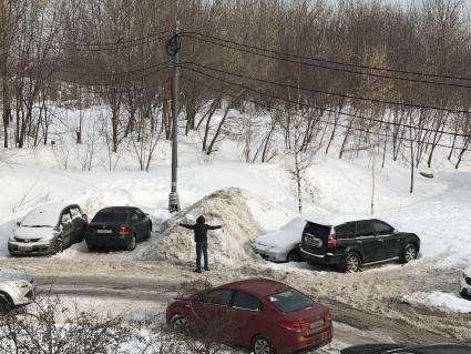 Москва.  Мужчина стоит у засыпанного снегом  автомобиля.