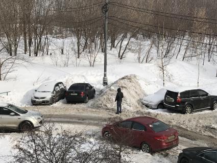 Москва.  Мужчина стоит у засыпанного снегом  автомобиля.