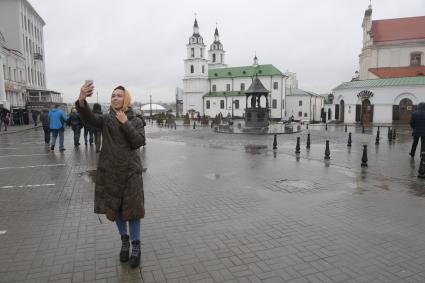 Беларусь, Минск. Девушка фотографируется на площади Свободы у ратуши.