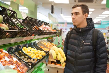 Самара.  Мужчина выбирает фрукты в продуктовом магазине.