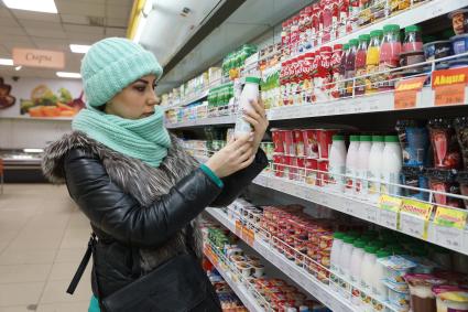 Самара. Девушка выбирает йогурт в продуктовом магазине.