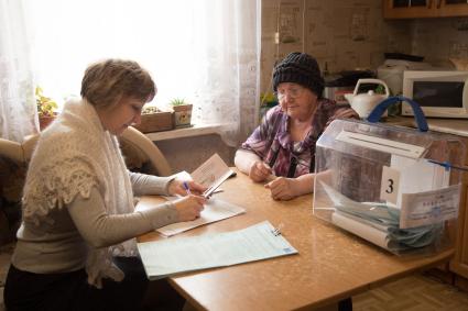 Ленинградская область, д. Большая Рассия. Член выездной избирательной комиссии  проводит голосование  на дому.
