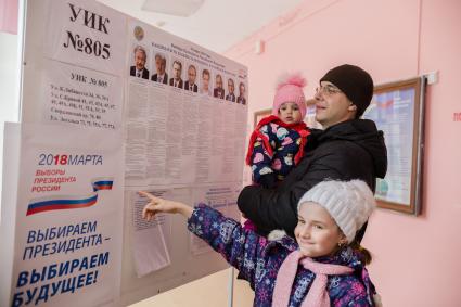 Челябинск. Мужчина с детьми у стенда с кандидатами на должность президента РФ на избирательном участке #805.