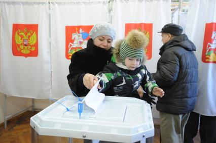 Московская область. Женщина с ребенком во время голосования на выборах президента РФ на избирательном участке.