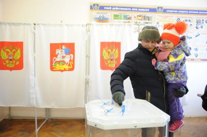 Московская область.   Мужчина с ребенком во время голосования на выборах президента РФ на избирательном участке.