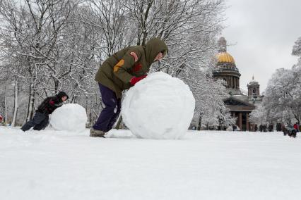 Санкт-Петербург. Мама с сыном лепят снеговика в Александроском парке, около Исаакиевского собора.