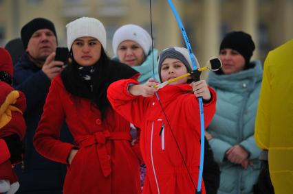 Москва.  Мальчик стреляет из лука во время  масленичных гуляний в  парке Горького.