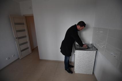 Москва. Мужчина на кухне  в квартире нового дома ,  построенного  в рамках программы реновации на бульваре Рокоссовского.