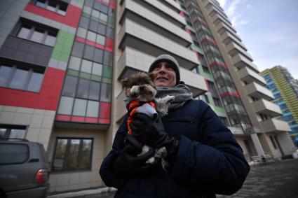 Москва. Мужчина с собакой у нового  дома ,  построенного  в рамках программы реновации на бульваре Рокоссовского.