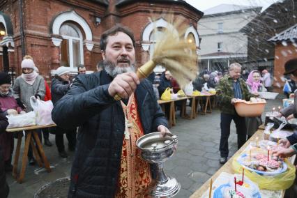 Барнаул. Священнослужитель освящает пасхальные куличи и яйца.