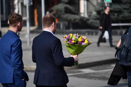 Москва. Мужчина с букетом цветов переходит улицу.