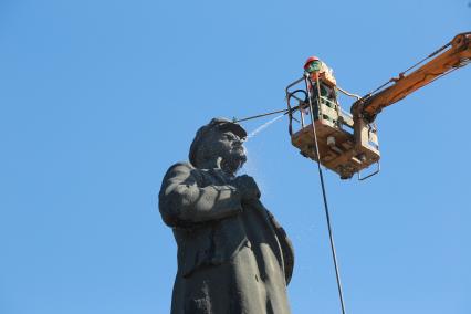 Красноярск.   Сотрудник коммунальных служб моют памятник  В.И. Ленину на одной из улиц города.