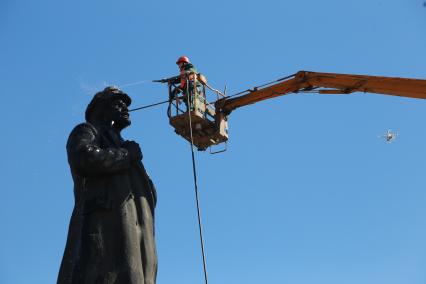 Красноярск.   Сотрудники коммунальных служб моют памятник  В.И. Ленину на одной из улиц города.