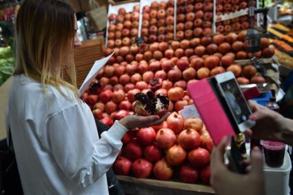 Москва. Девушка держит спелый гранат на Даниловском рынке.