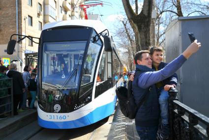Москва.  Мужчина с ребенком фотографируется во время парада ретро трамваев, посвященного 119-летию трамвайного движения в городе.