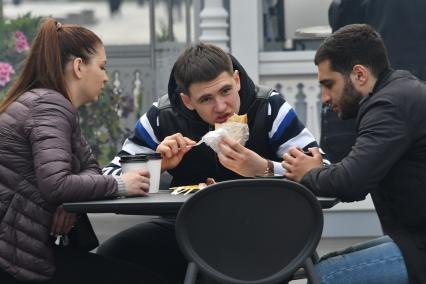 Москва. Молодые люди едят на улице.