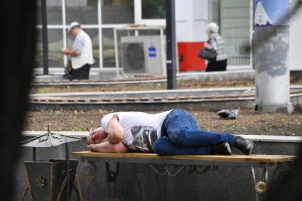 Москва.  Мужчина спит на скамейке на одной из улиц города.