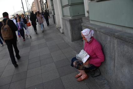 Москва.  Женщина просит милостыню у прохожих.