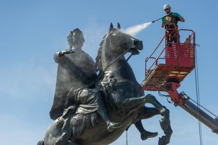 Санкт-Петербург. Работник музея Городской скульптуры моет памятник Петру I `Медный всадник` на Сенатской площади.