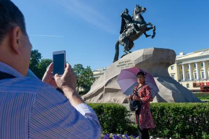 Санкт-Петербург.  Женщина фотографируется на фоне памятника Петру I `Медный всадник` на Сенатской площади.