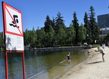 Москва. Женщина фотографирует девочку у водоема.