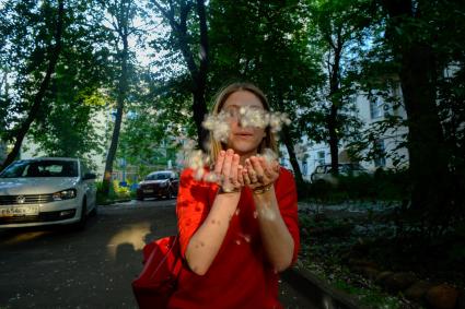 Москва. Девушка держит в руках тополиный пух в Хлебном переулке.