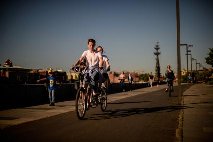Москва.  Молодые люди на велосипедах на Крымской набережной.