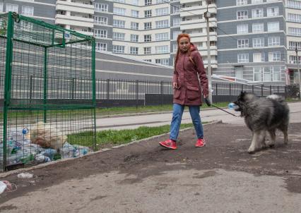 Пермь. Девушка с собакой выбрасывает мусор в контейнер для раздельного сбора пластиковых бутылок.