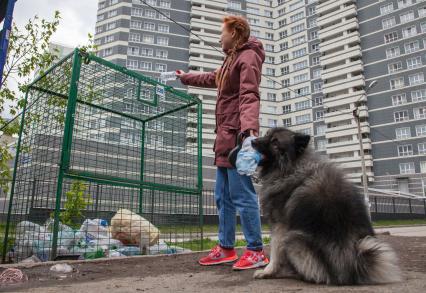 Пермь. Девушка выбрасывает мусор в контейнер для раздельного сбора пластиковых бутылок.